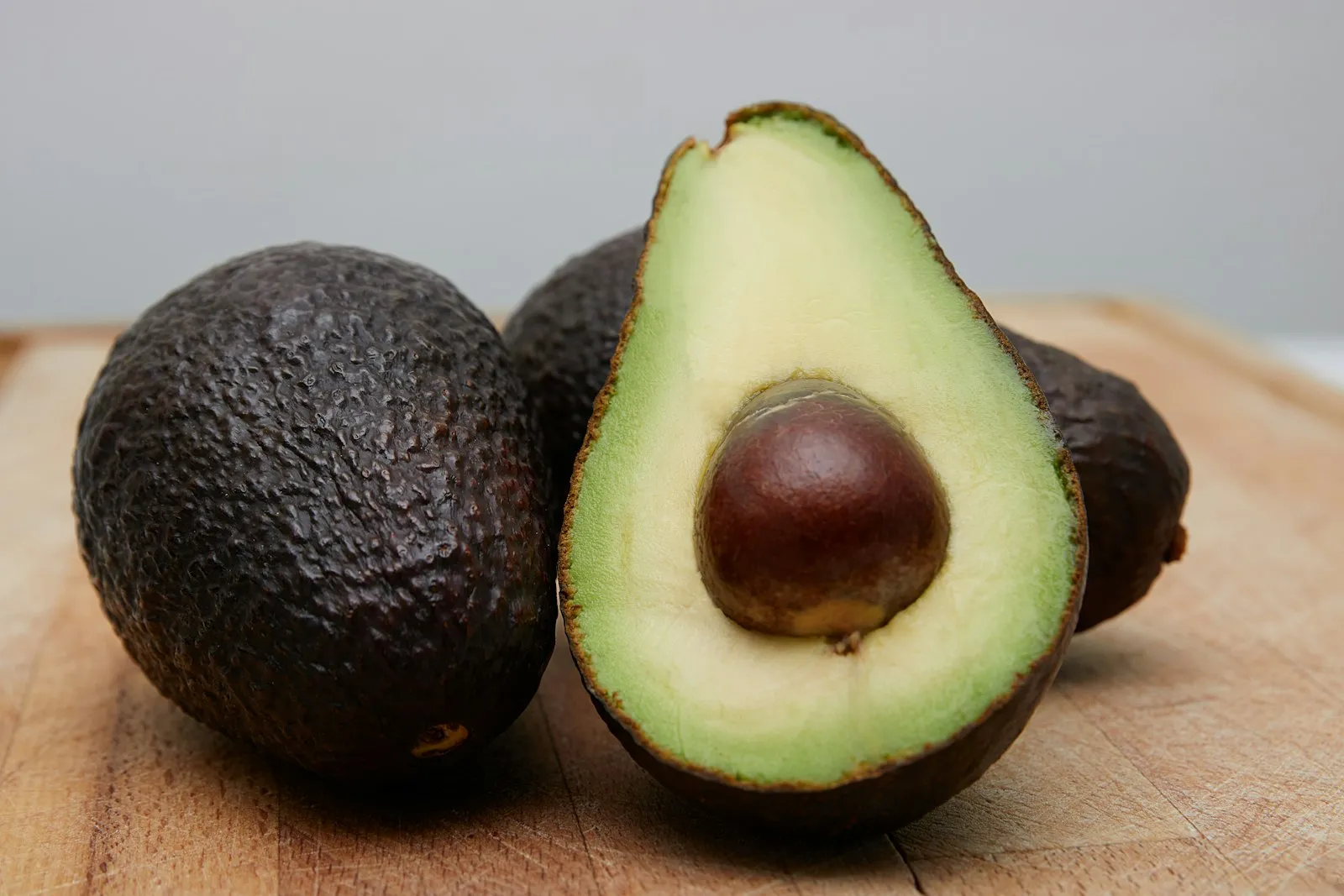 Whole and halved avocados arranged on a neutral background