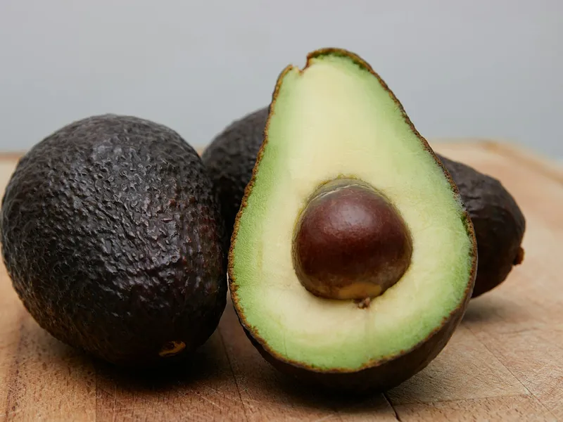 Whole and halved avocados arranged on a neutral background
