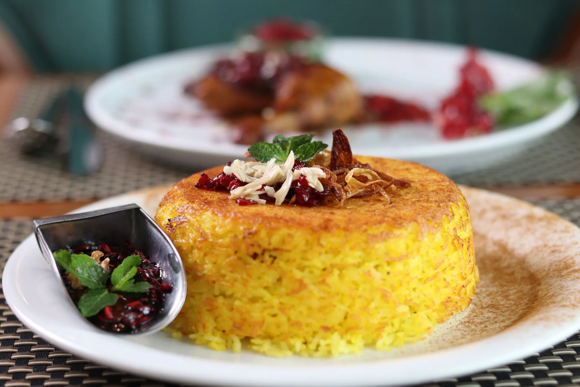 A round mold of bright golden turmeric rice on a plate, topped with herbs and a side of garnish